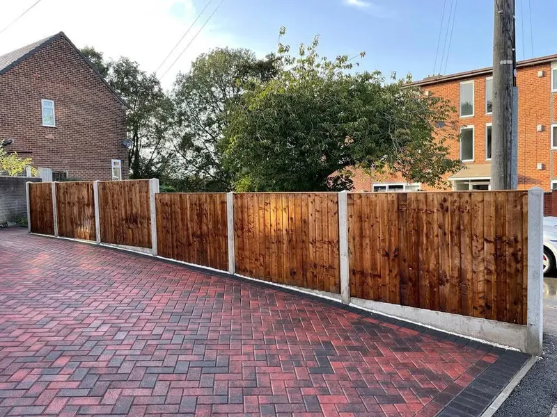 Close view of a brindle block doorstep with charcoal bullnose kerbs and perpendicular charcoal edging, opening onto herringbone paving beside a brick wall and channel drain.