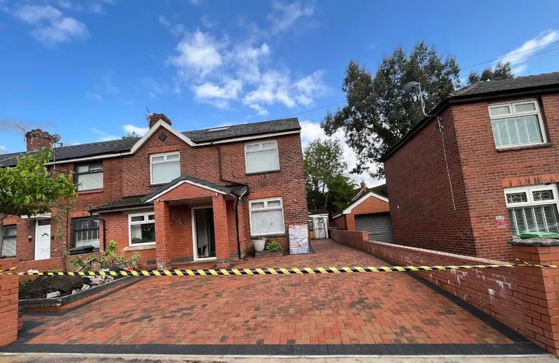 Charcoal herringbone patio wrapping a brick conservatory, narrowing into a side path with a single cream header border along the house, conservatory and fence lines.