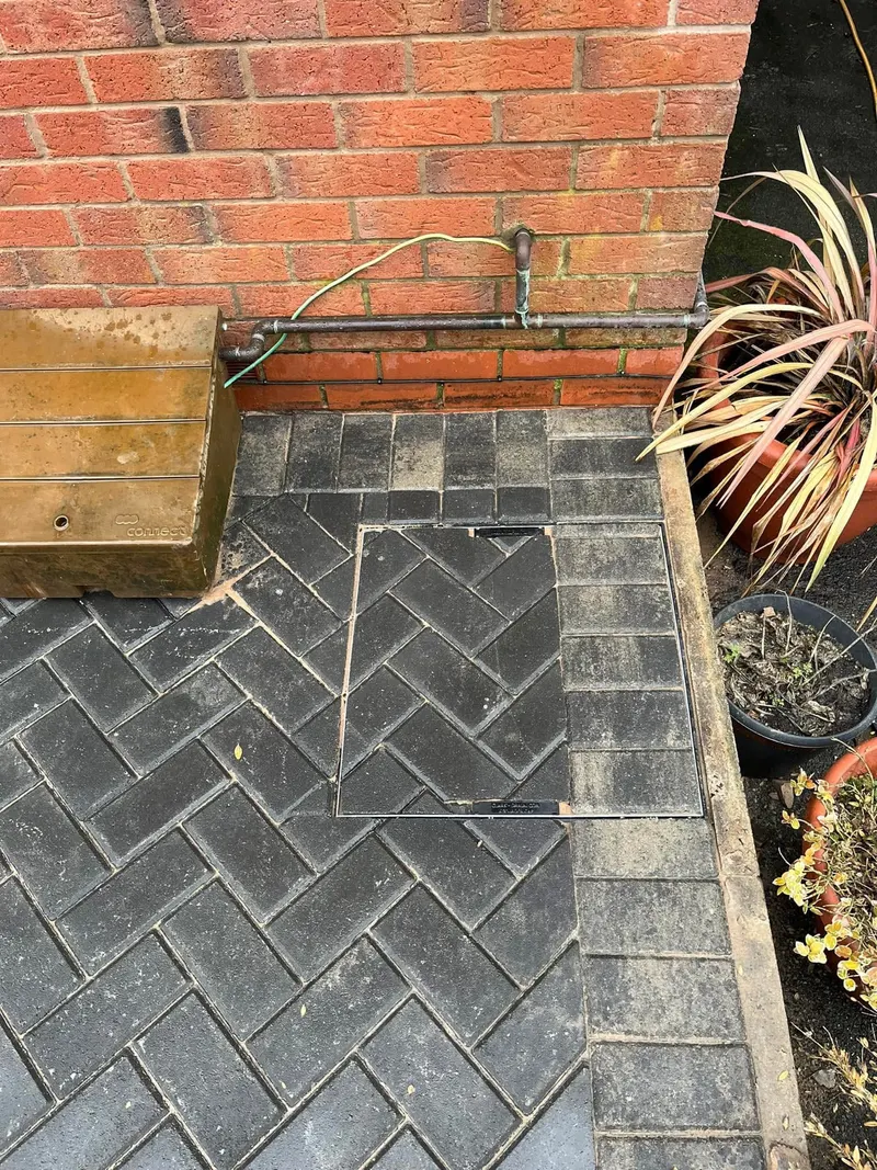 Charcoal herringbone front drive and path with buff block borders following the house line, including a raised step with buff sides and charcoal top before a grey door.