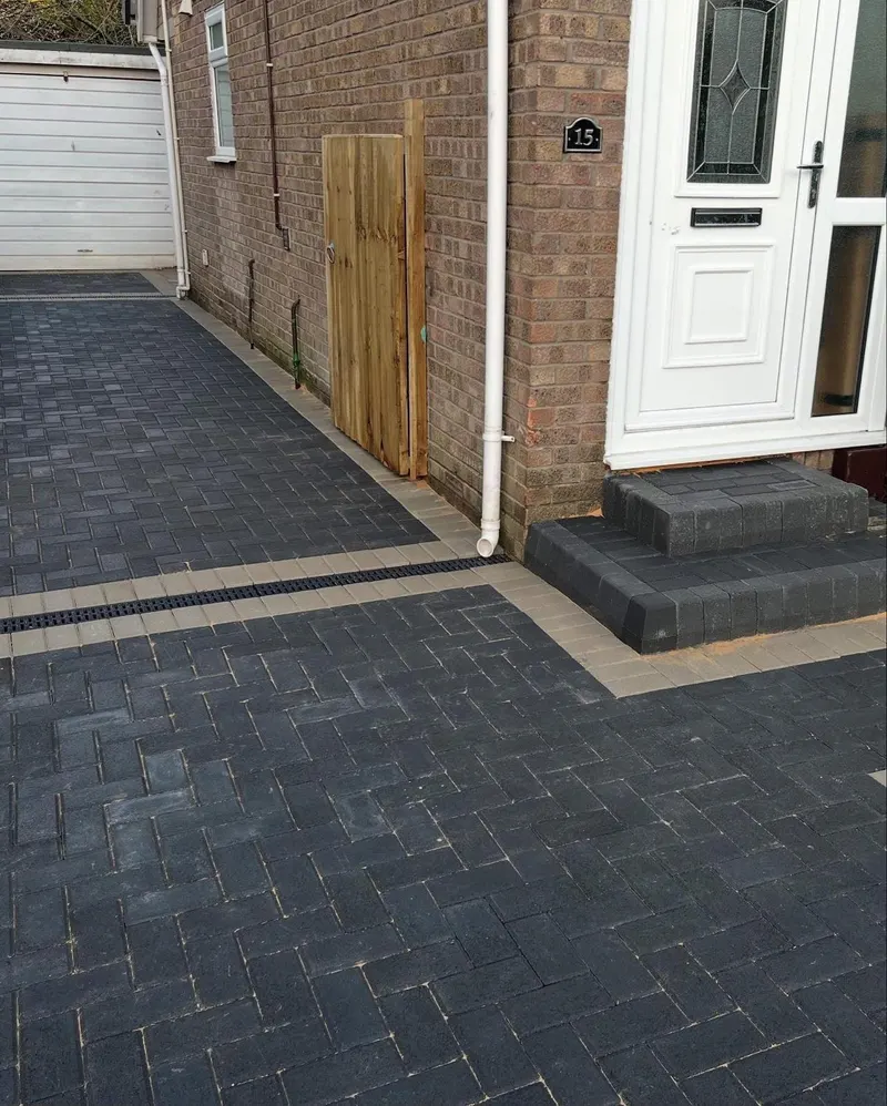Large red-toned herringbone block driveway edged in dark blocks, enclosed by low red brick walls with stone copings.