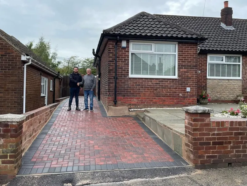 Charcoal, grey and buff block paving on a front apron and narrow side path, bordered in dark blocks on a brick semi.