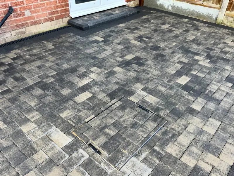 Two people shaking hands on a new red and charcoal brindle herringbone block driveway with a dark double border.