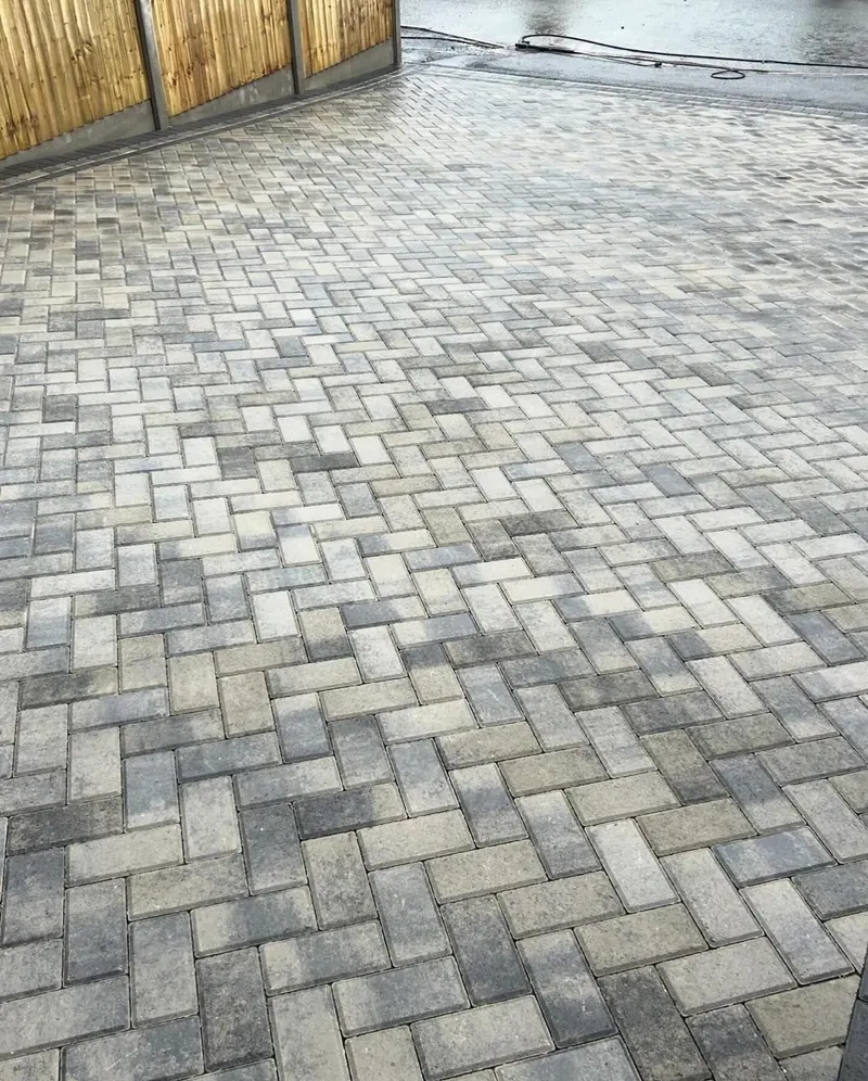 Red brindle block paving in staggered bond with a charcoal soldier border, laid across a wide front apron on brickwork.