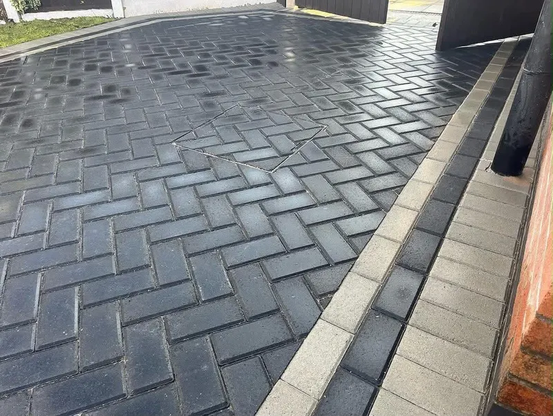 Charcoal herringbone block paving with silver and dark borders forming paths around a rectangular front lawn on a brick semi.