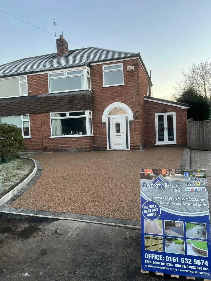 Broad amber-toned resin bound driveway and side path with dark grey block borders in front of a red brick semi-detached house on a frosty morning.