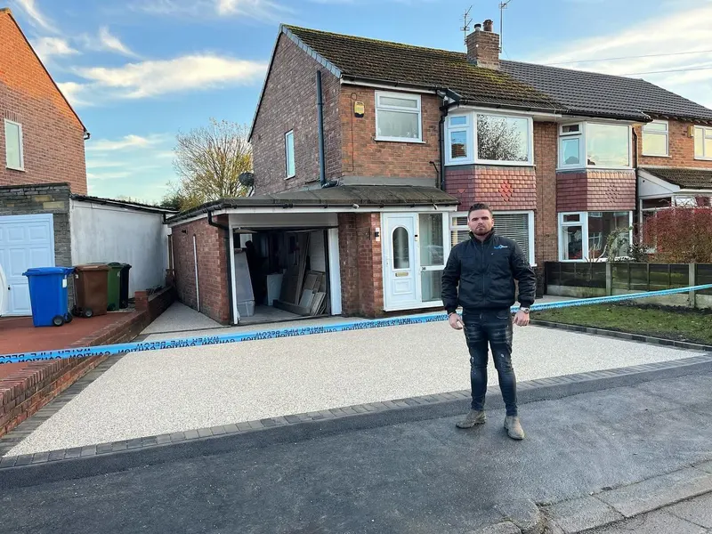 New buff resin bound driveway with dark grey block borders in front of a brick semi-detached house, sealed with blue barrier tape.