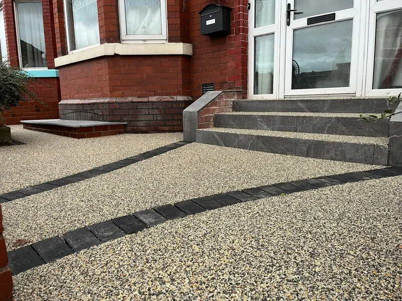 Light tan resin bound approach with parallel charcoal block lines leading to wide slate-faced steps with resin treads at a red brick entrance.